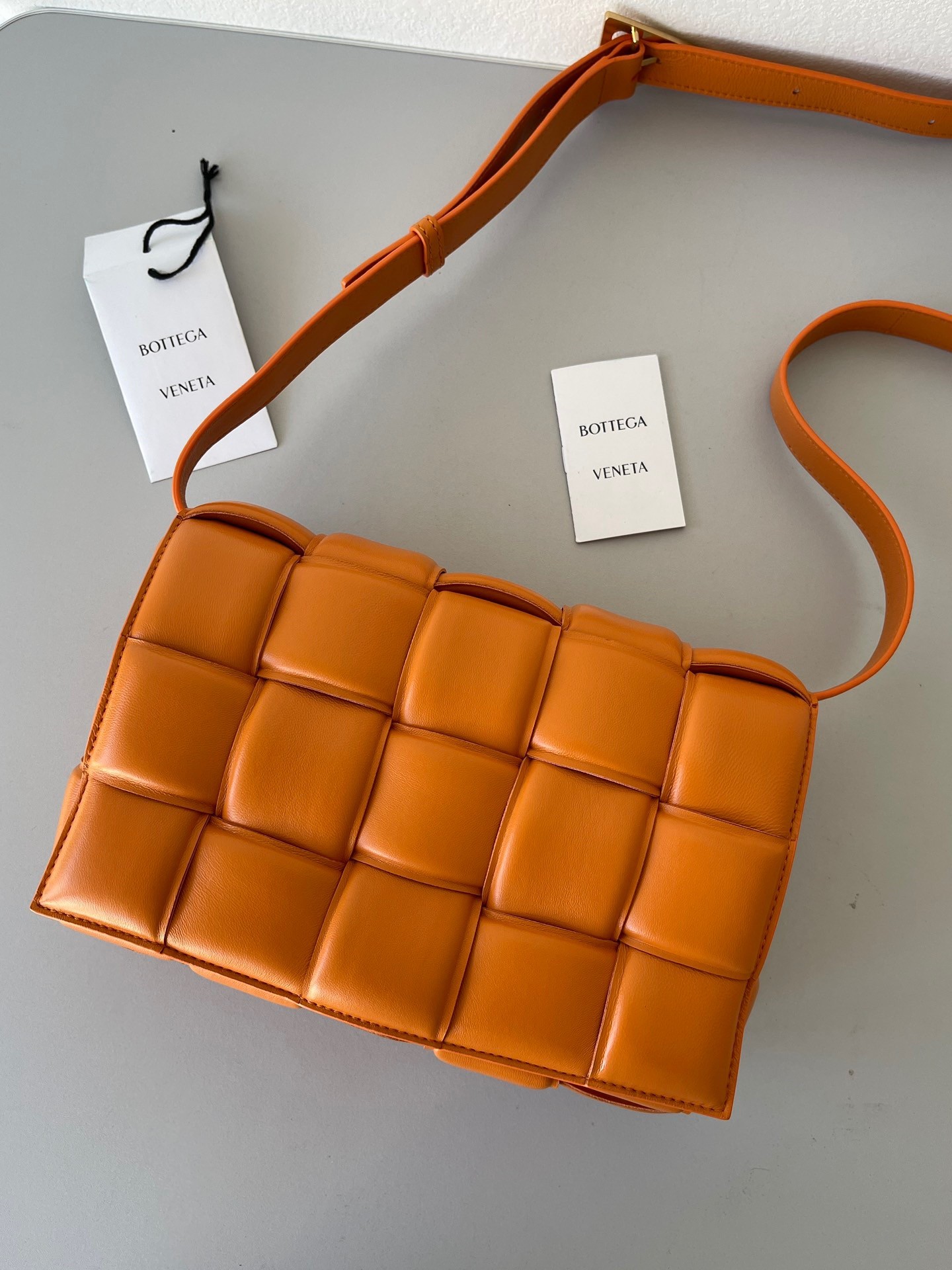 bo*te*ga Ve*ne*ta padded cassette bag in orange lambskin