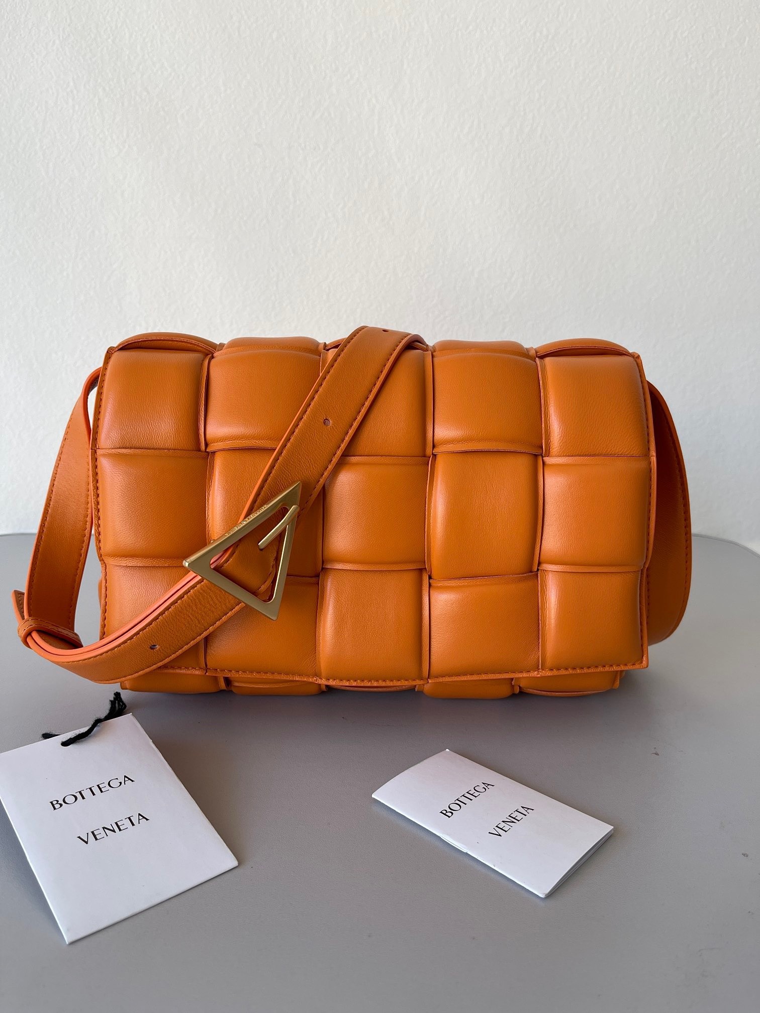 bo*te*ga Ve*ne*ta padded cassette bag in orange lambskin